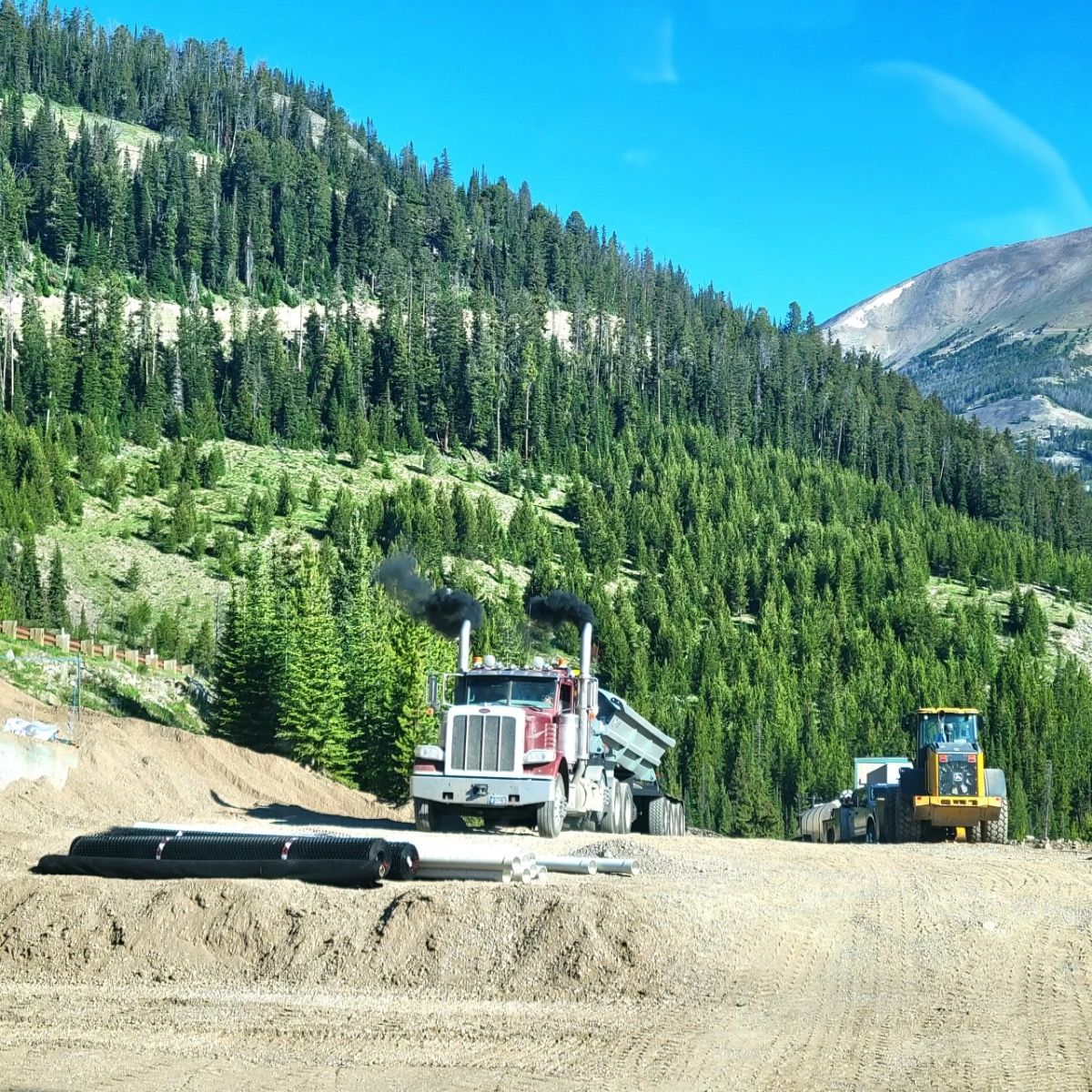 A dump truck is driving down a dirt road in the mountains