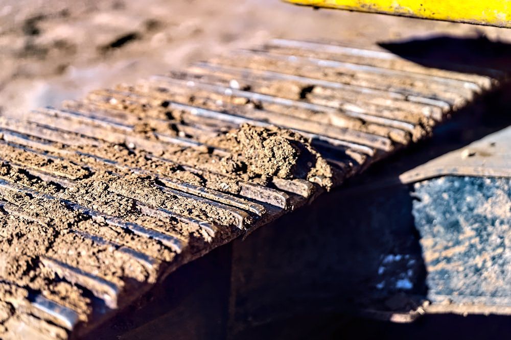 A close up of the tracks of a bulldozer on a dirt road.