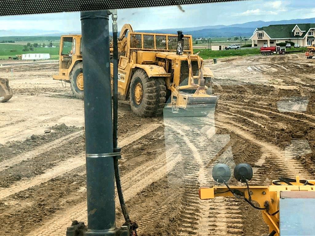 A large yellow bulldozer is driving through a dirt field.