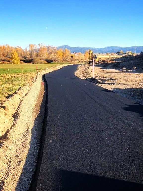 A road that is going through a field with mountains in the background