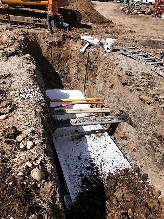 A construction worker is digging a trench in the dirt.
