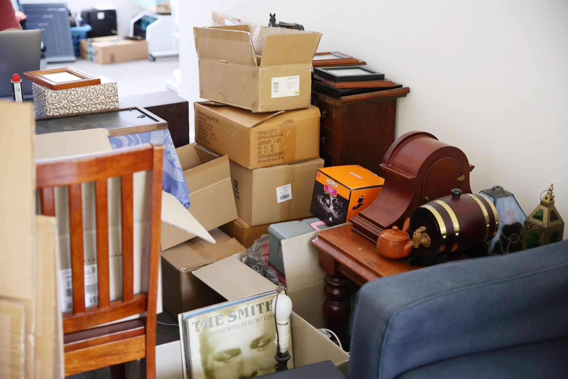 Pile of packed boxes and furniture in a room; moving out or in process.