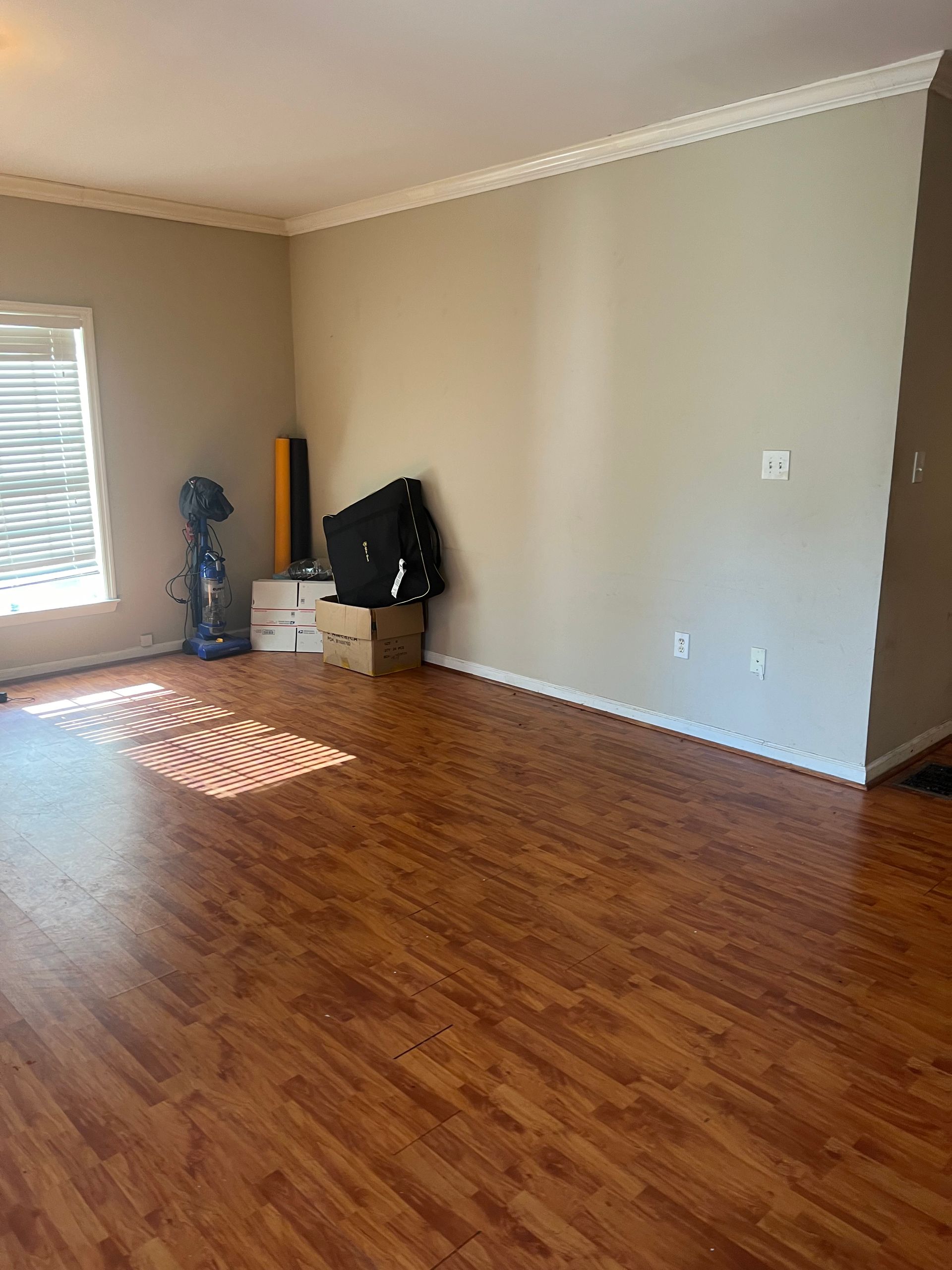 An empty living room with hardwood floors and a window.