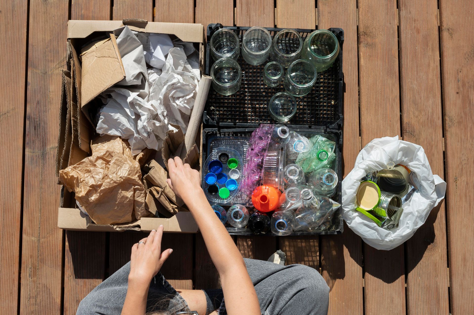 A child is sitting on a wooden deck playing with recycling.