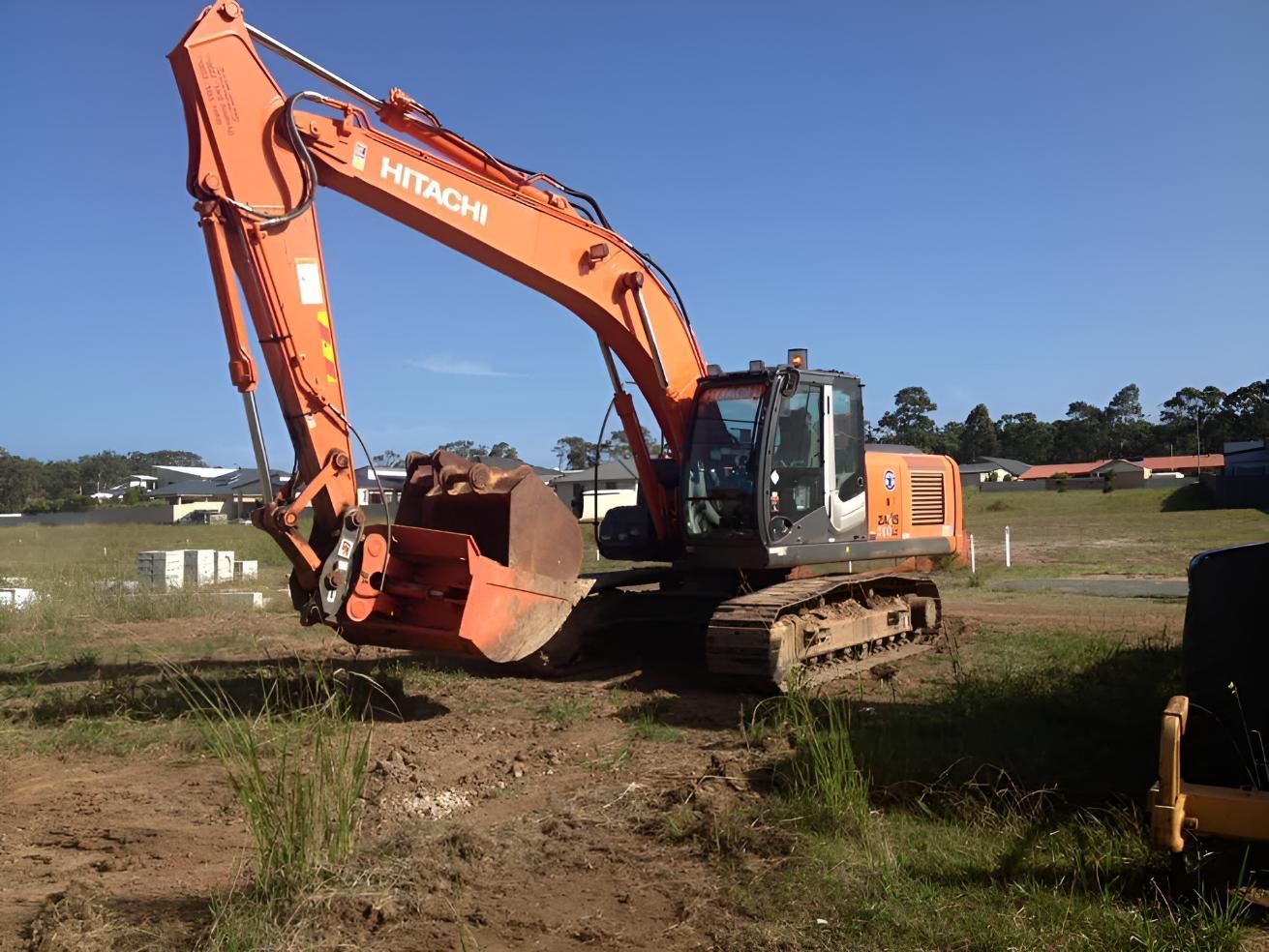 A Hitachi Excavator Is Parked In A Dirt Field — BB & F Constructions Pty Ltd In Taree, NSW