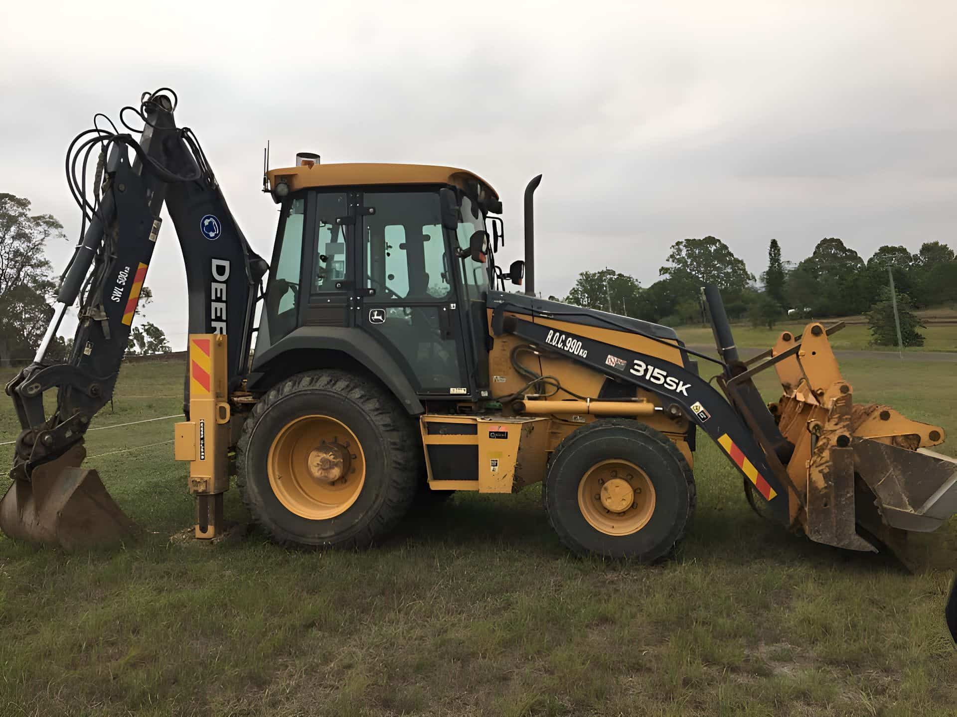 A yellow and black tractor is parked in a grassy field — BB & F Constructions Pty Ltd In Taree, NSW