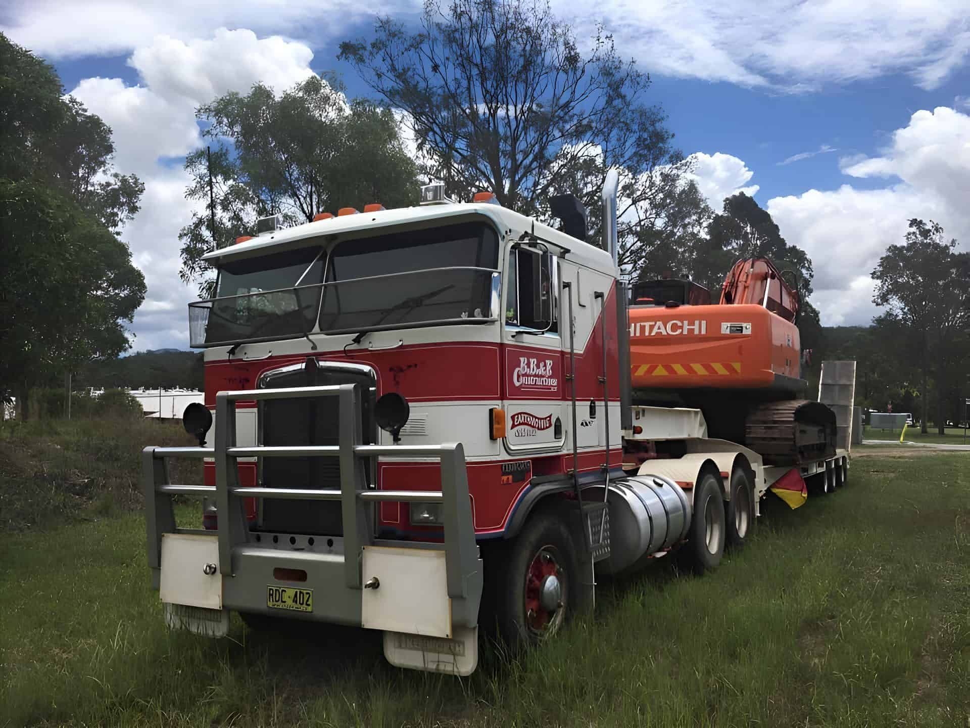 A red and white semi truck is parked in a grassy field — BB & F Constructions Pty Ltd In Taree, NSW