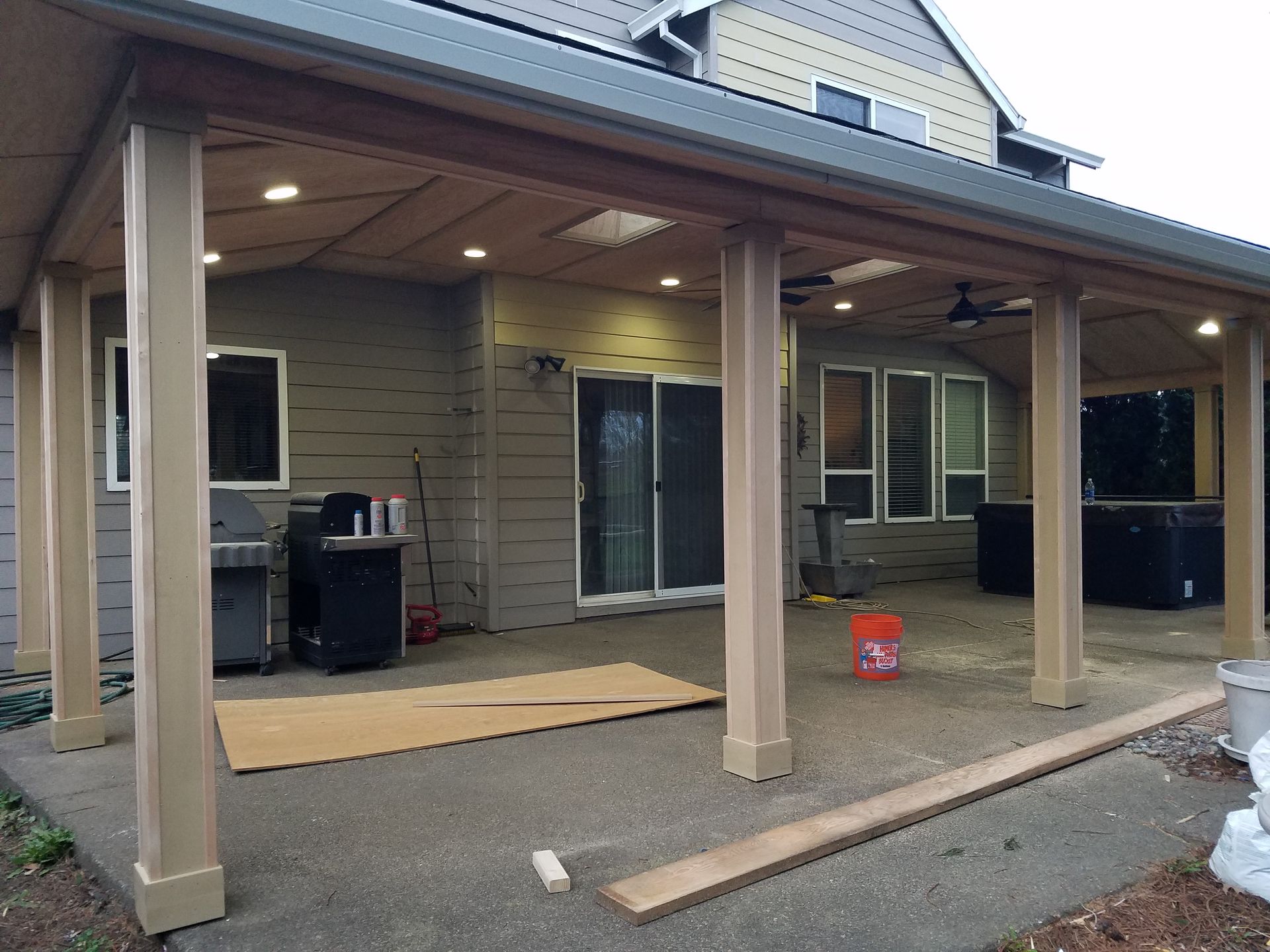 Covered patio extension with columns, lights, and a sliding glass door.