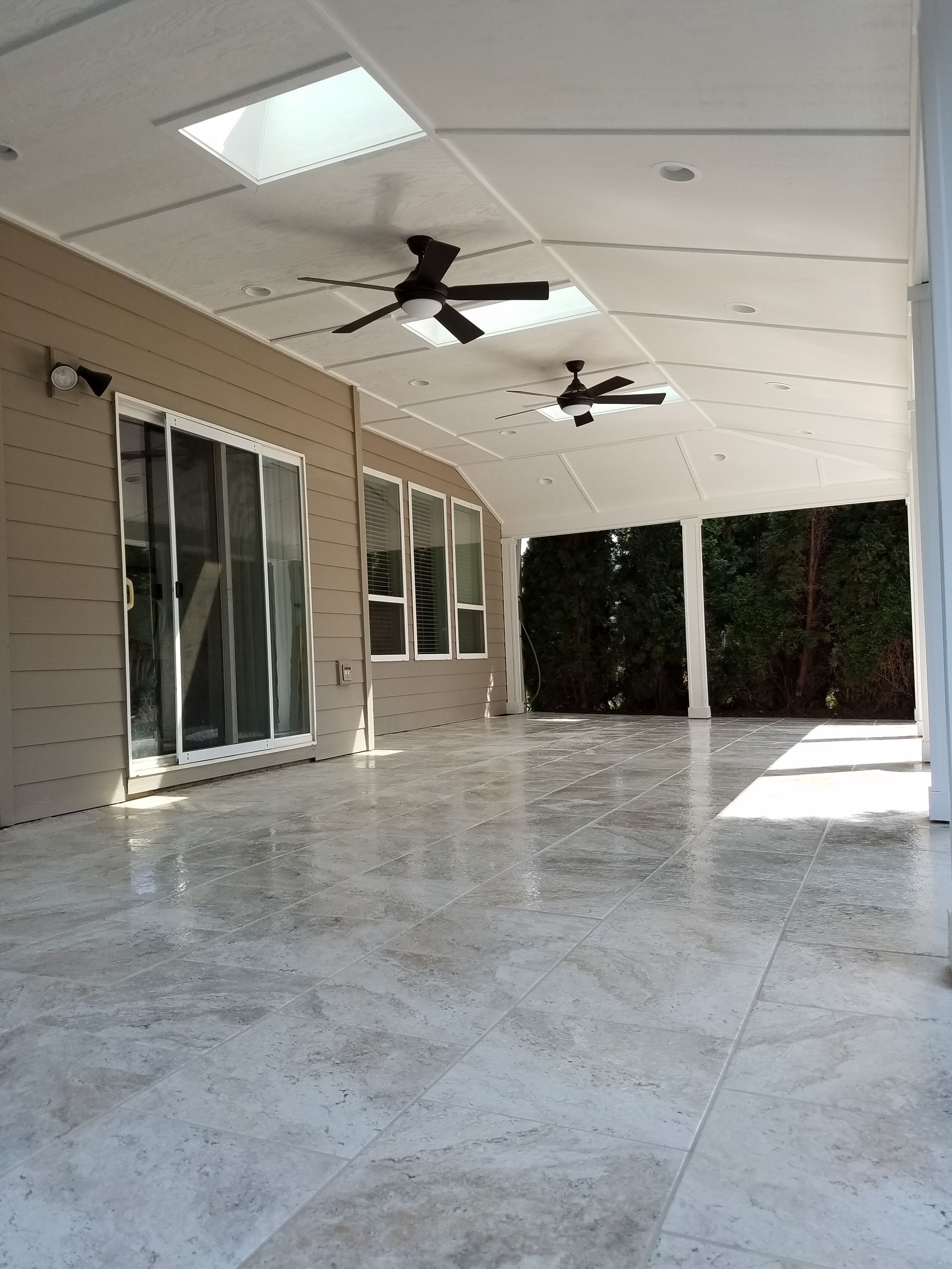 Covered outdoor patio with tile floor, skylights, and ceiling fans.