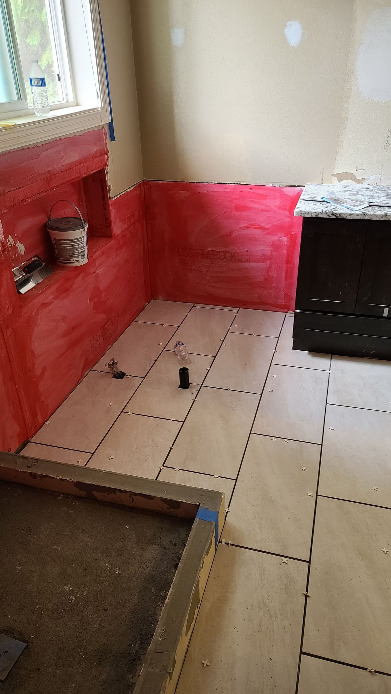 Bathroom under construction: Red waterproof membrane on walls, shower base, cement backer board floor, window.