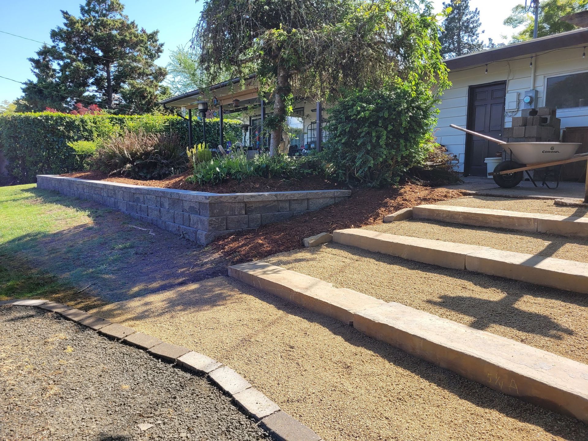 Concrete steps and retaining wall leading up to a house entrance with garden landscaping.