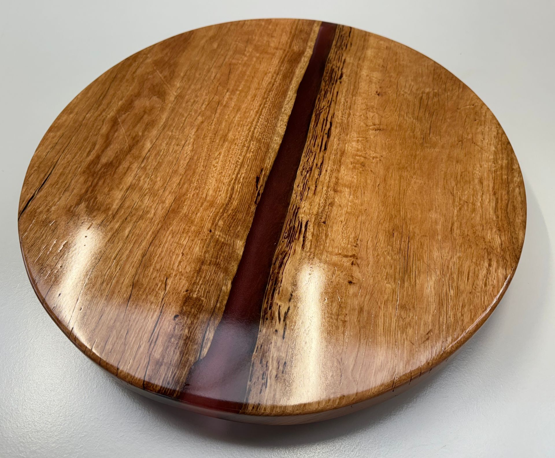 Wooden bowl with a red resin river, on a white surface.