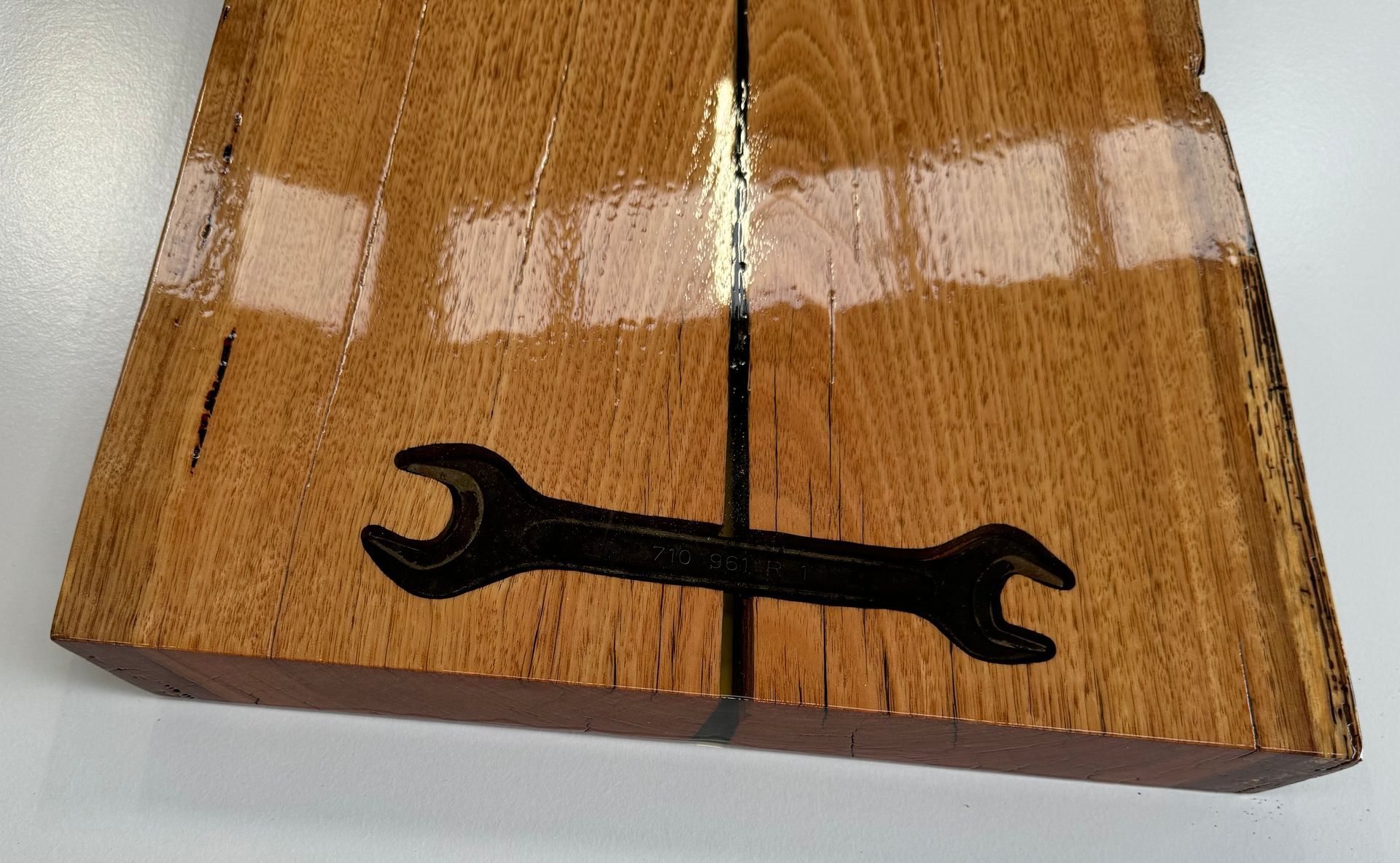 Wooden block with a wrench cutout, stained brown.