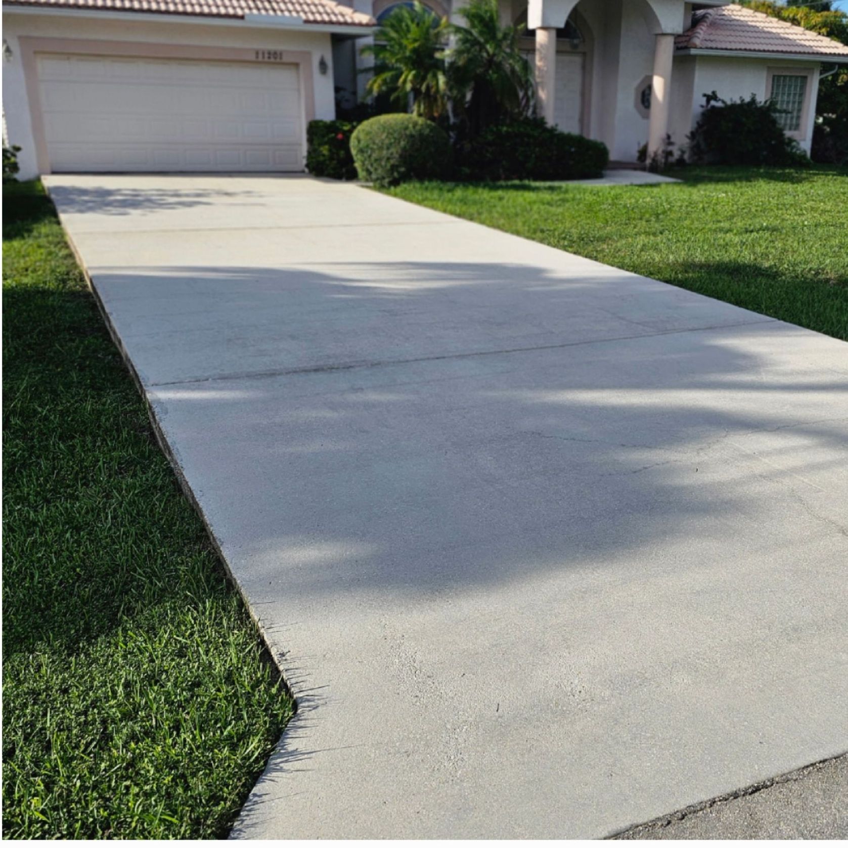 A concrete driveway leading to a house with a white garage door