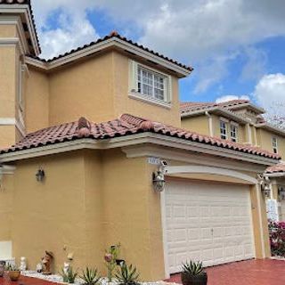 A large yellow house with a white garage door and a tile roof.