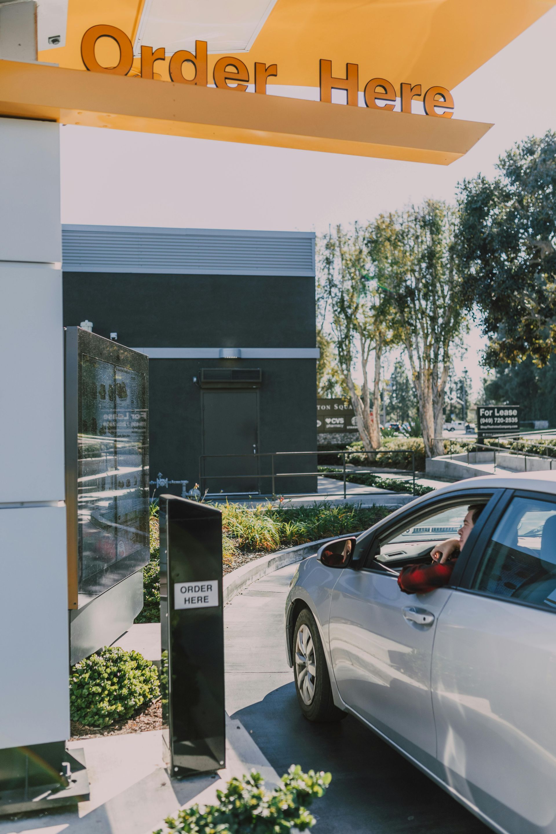 A car is parked under a sign that says order here