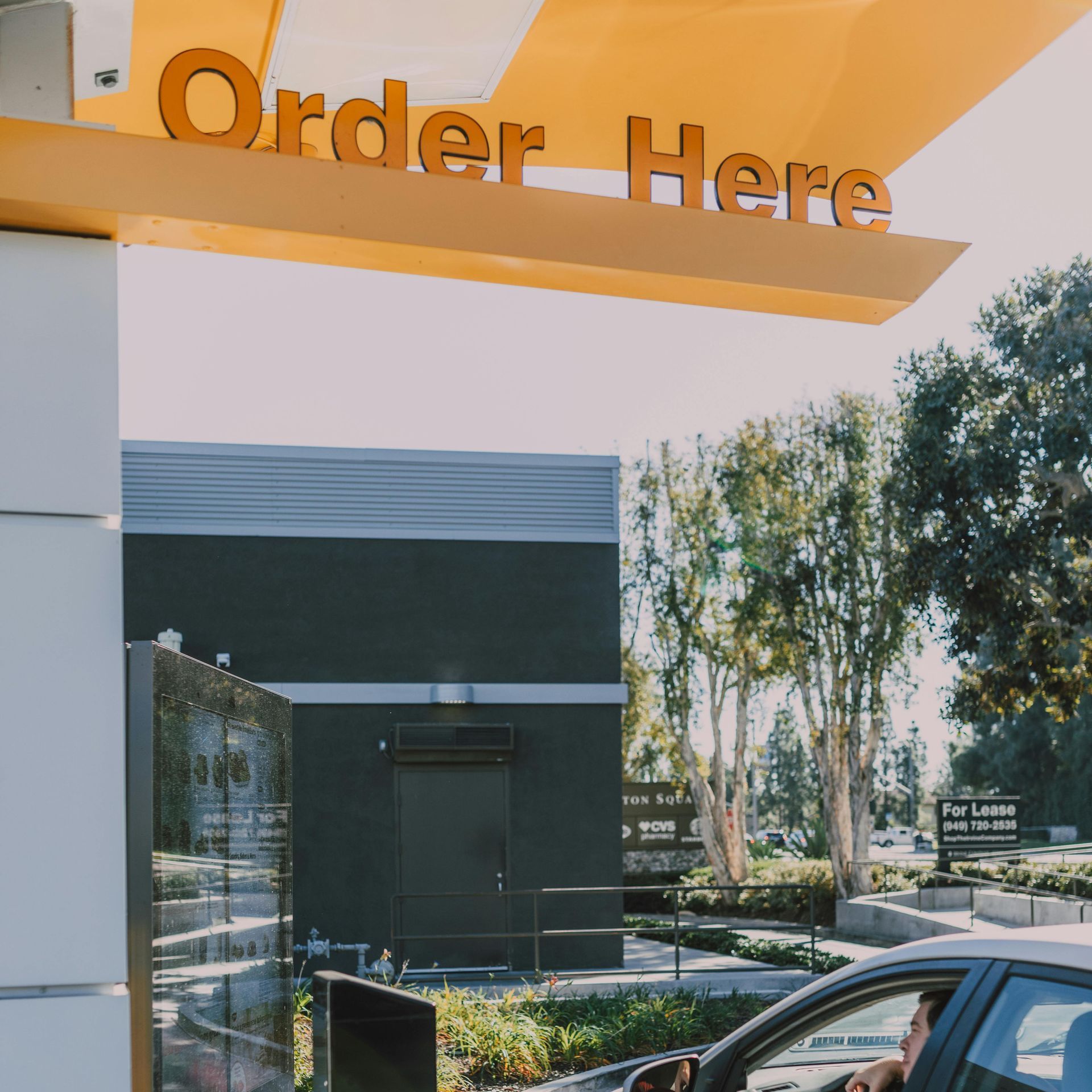 A man in a car drives past an order here sign