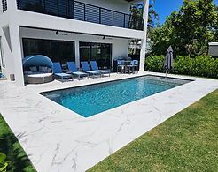 There is a large swimming pool in the backyard of a house.