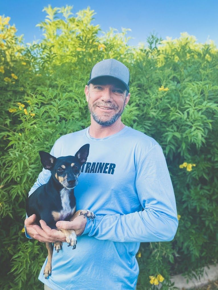 Chris Farr holding a small black dog.