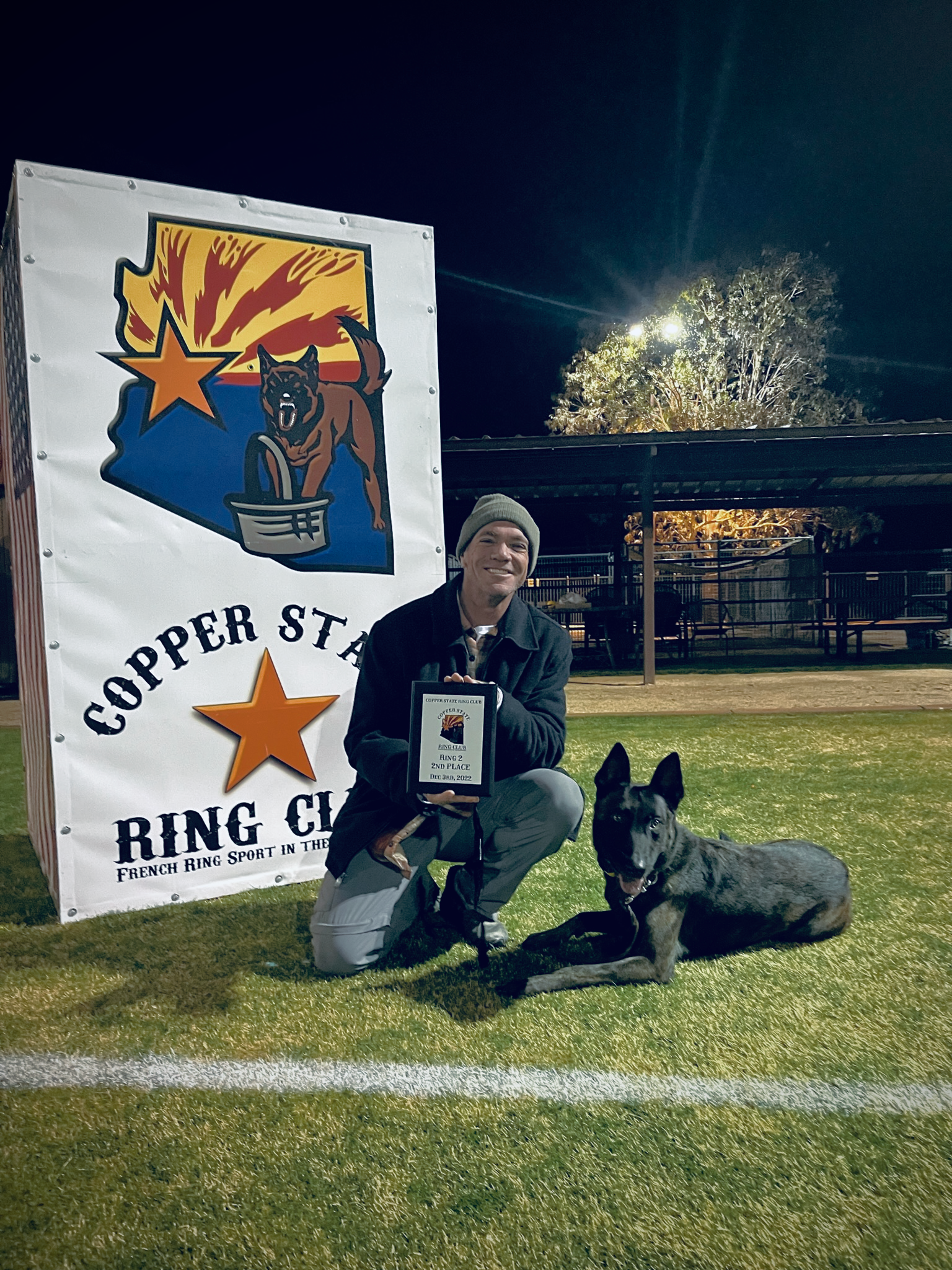 Chris Farr kneeling down next to a dog on a field.