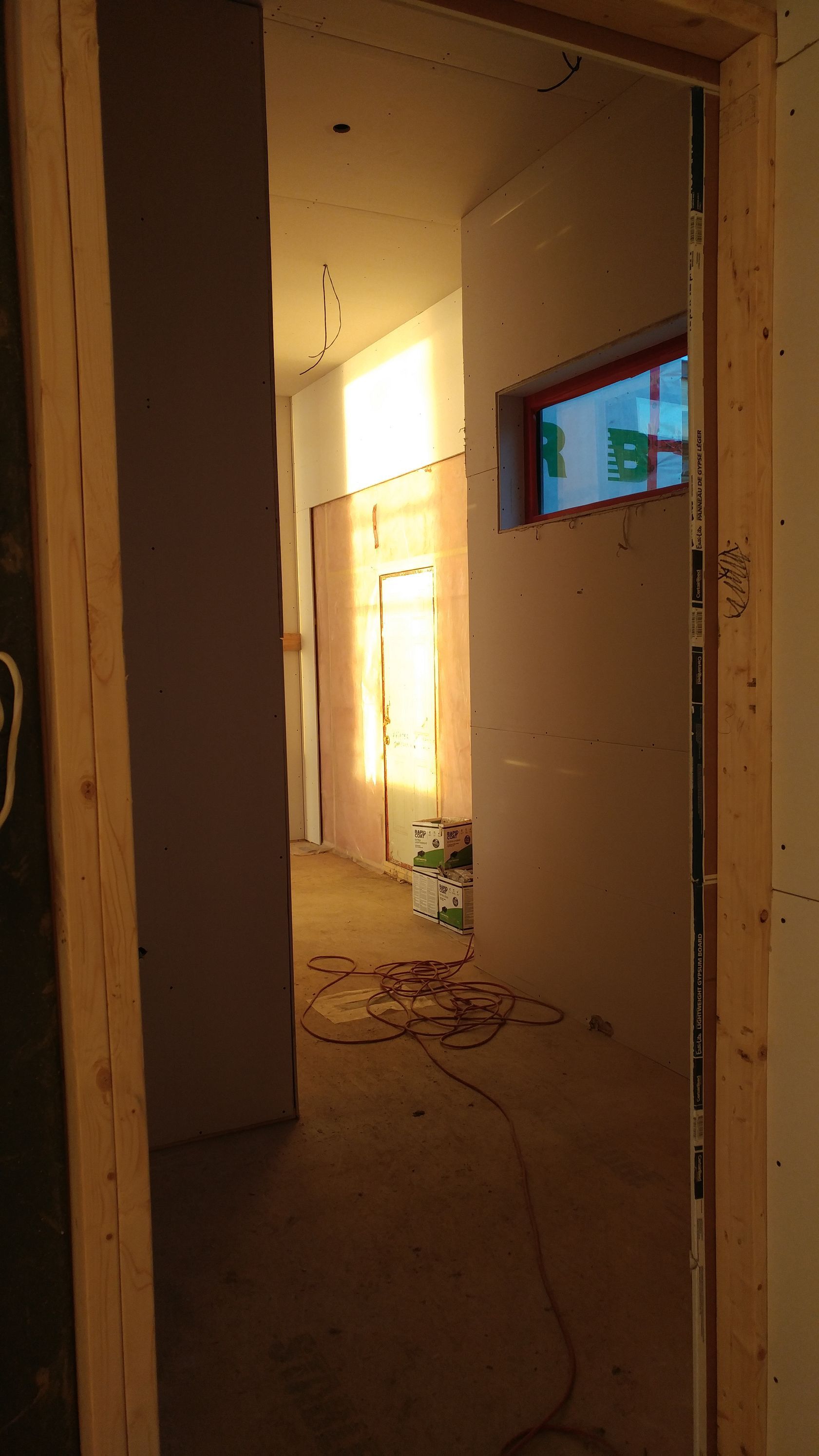 Un couloir dans un immeuble en construction avec une fenêtre au milieu.