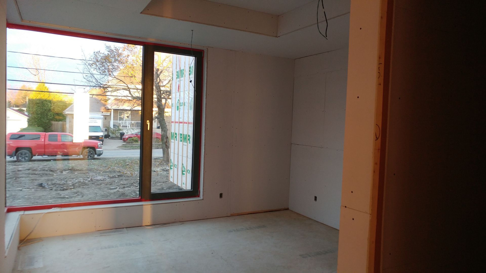 Une pièce vide avec une grande fenêtre et un camion rouge en arrière-plan.