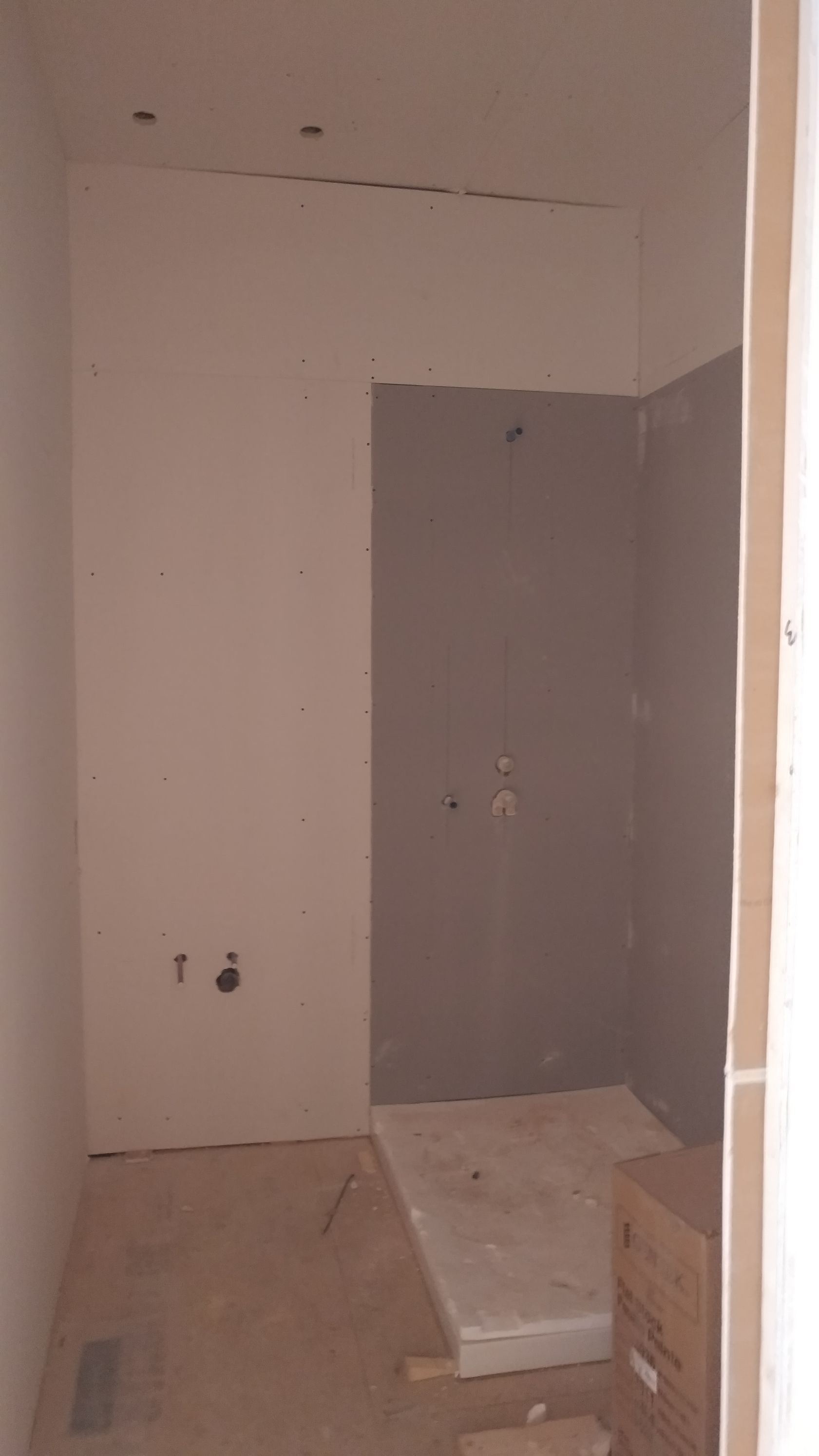 Une salle de bain en construction avec une cabine de douche et un box au sol.