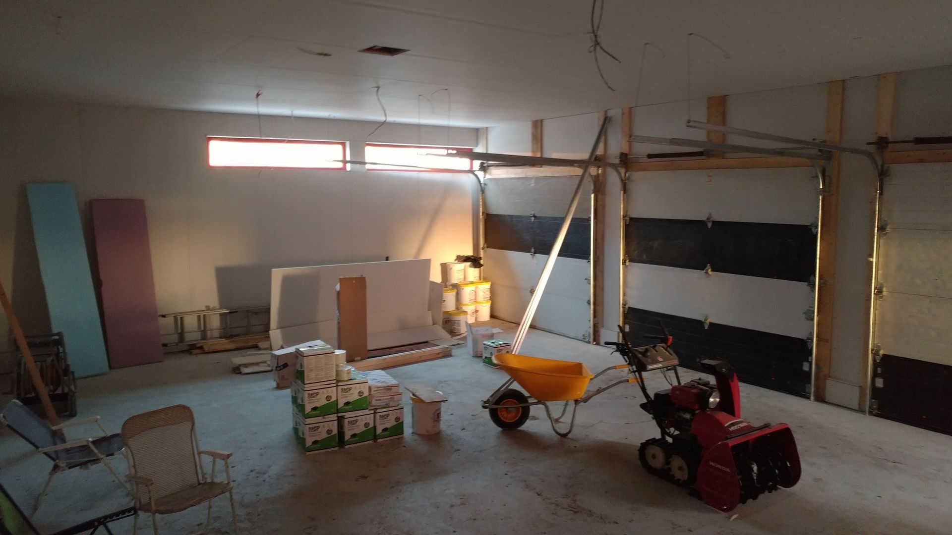 Il y a une brouette et une souffleuse à neige dans le garage.