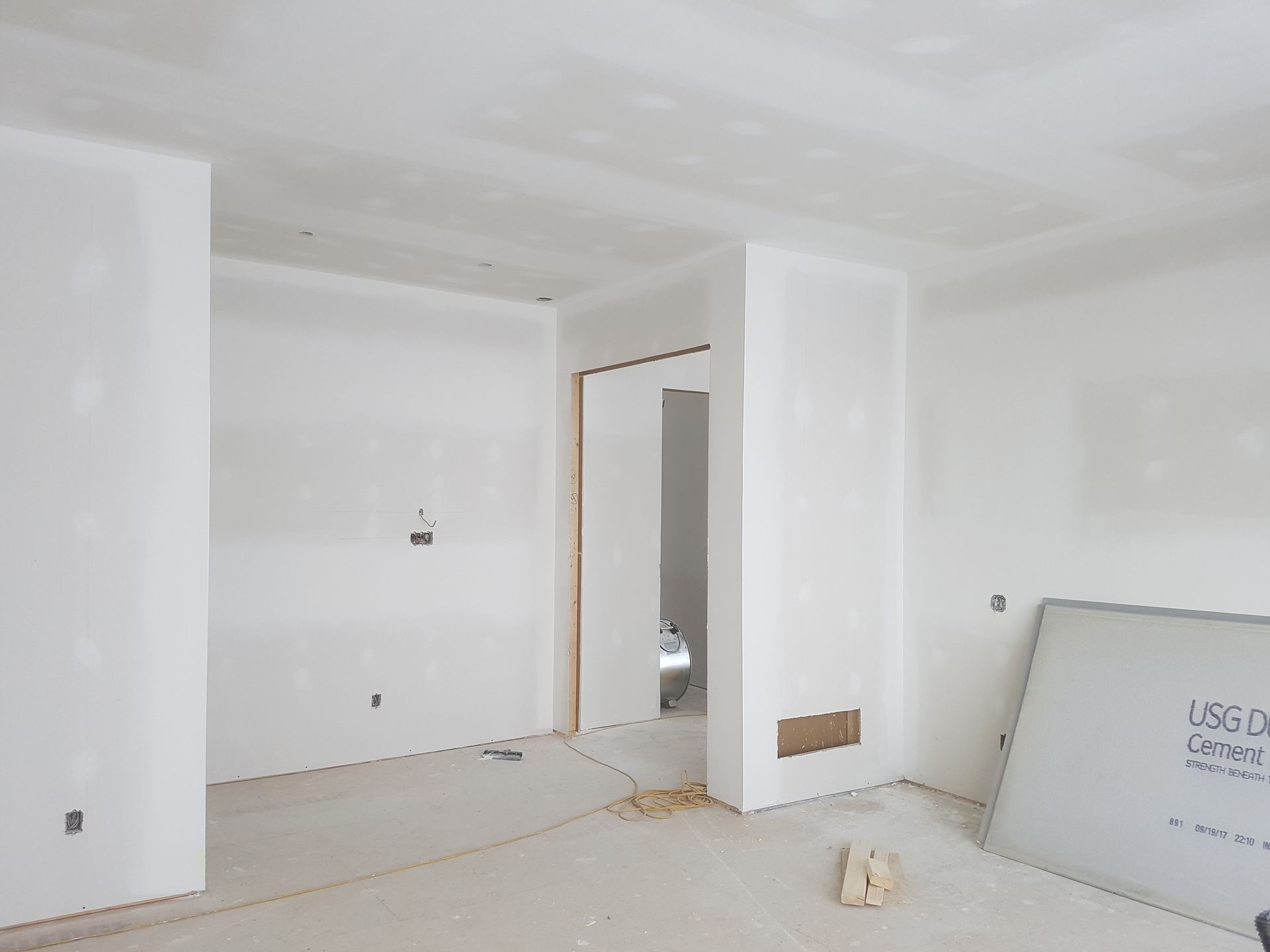 Une pièce vide avec des murs blancs et un tableau blanc sur le sol.