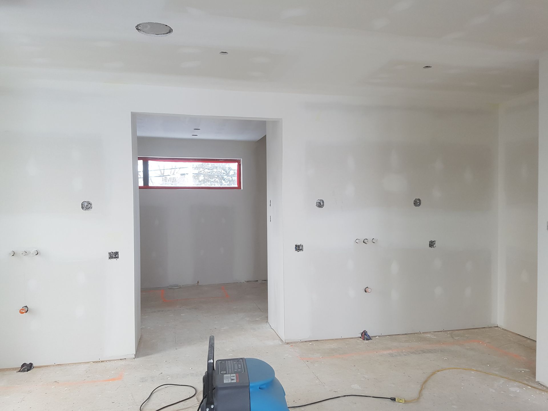 Une pièce vide avec des murs blancs et un aspirateur sur le sol.