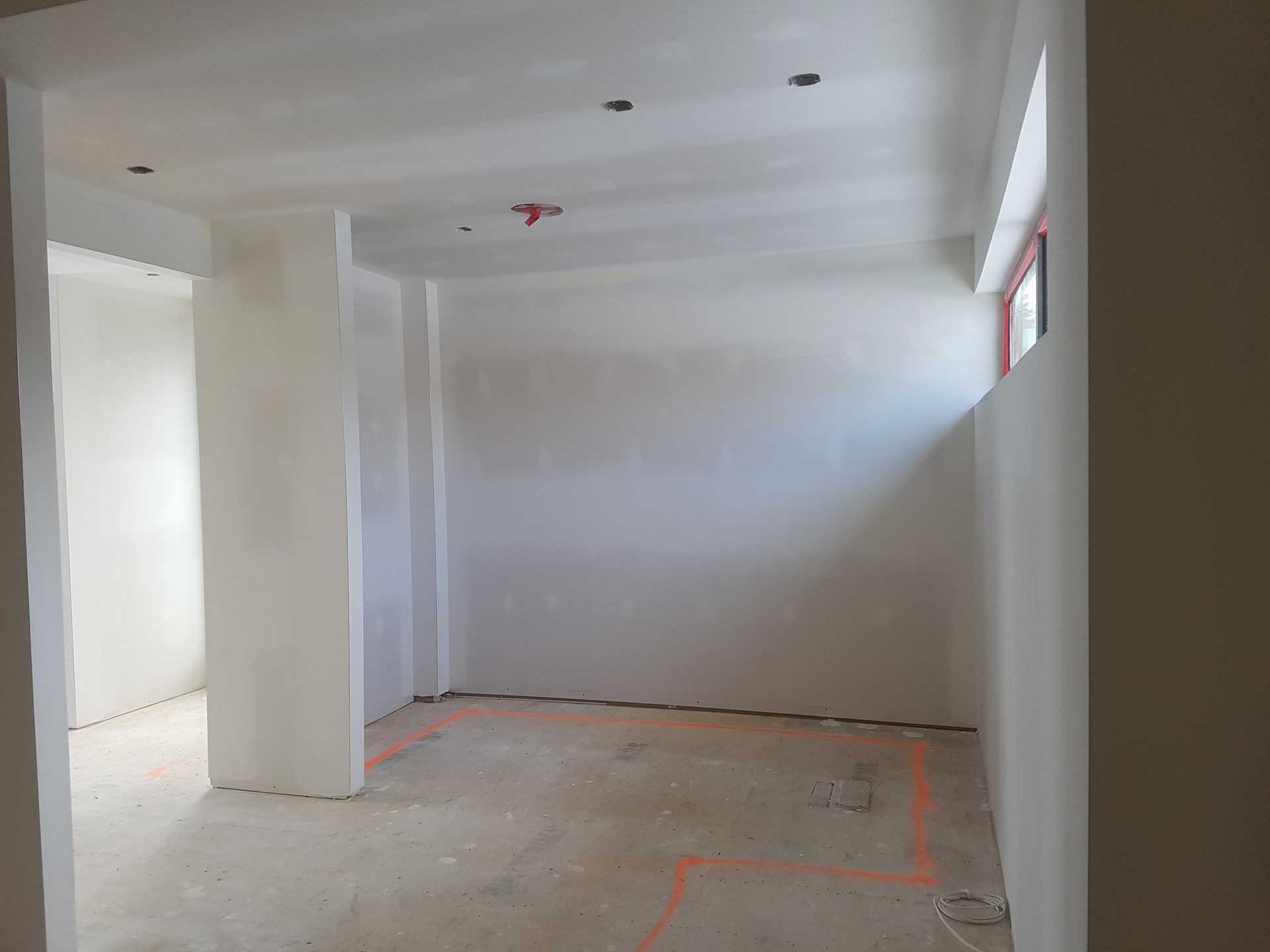 Une pièce vide avec des murs blancs et une fenêtre.