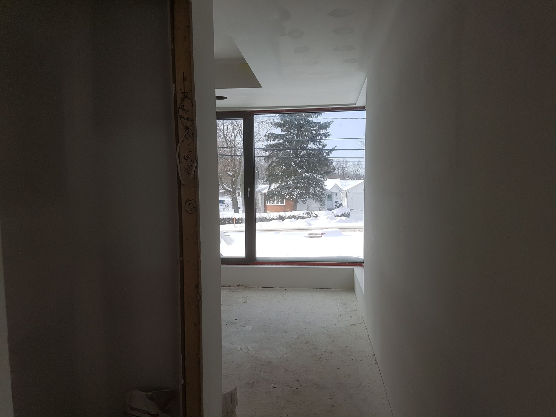 Un couloir avec une grande fenêtre et un arbre en arrière-plan