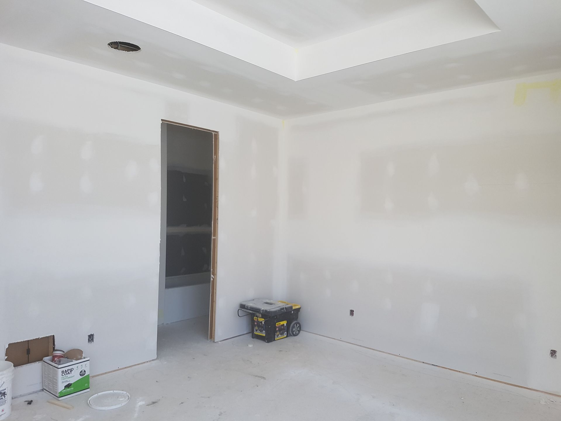 Une pièce vide avec des murs blancs et une boîte jaune sur le sol.