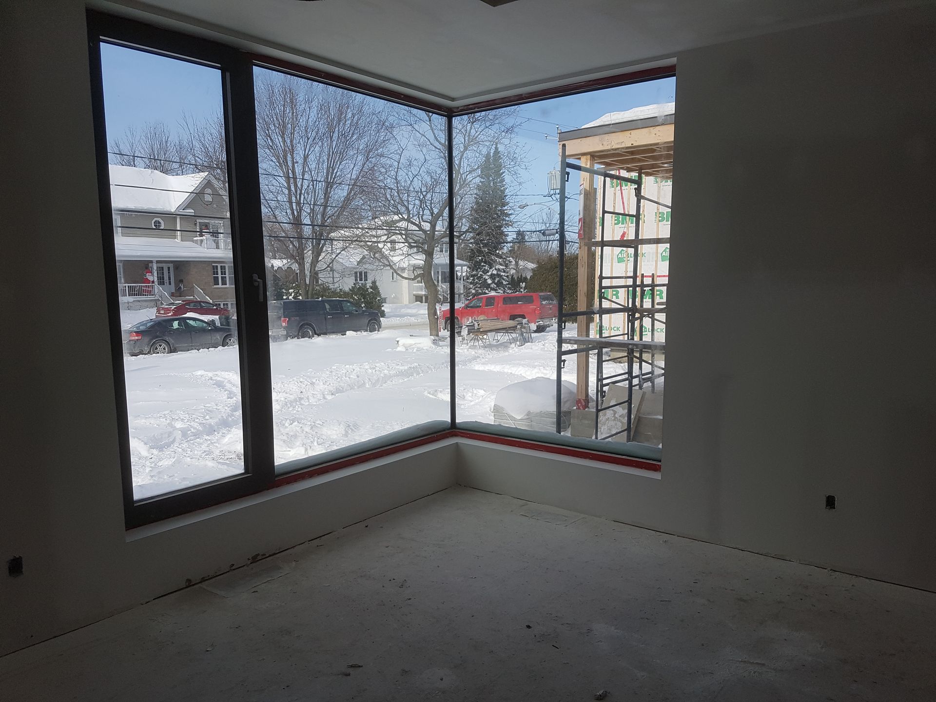 Une pièce avec beaucoup de fenêtres et une vue sur une rue enneigée.