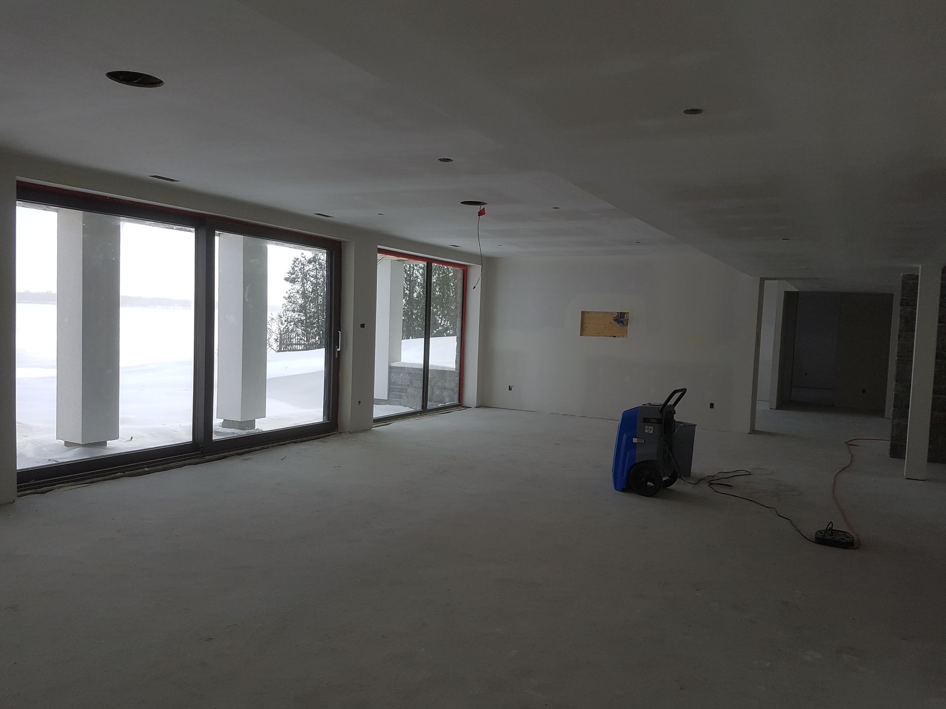 Une pièce vide avec beaucoup de fenêtres et un aspirateur.