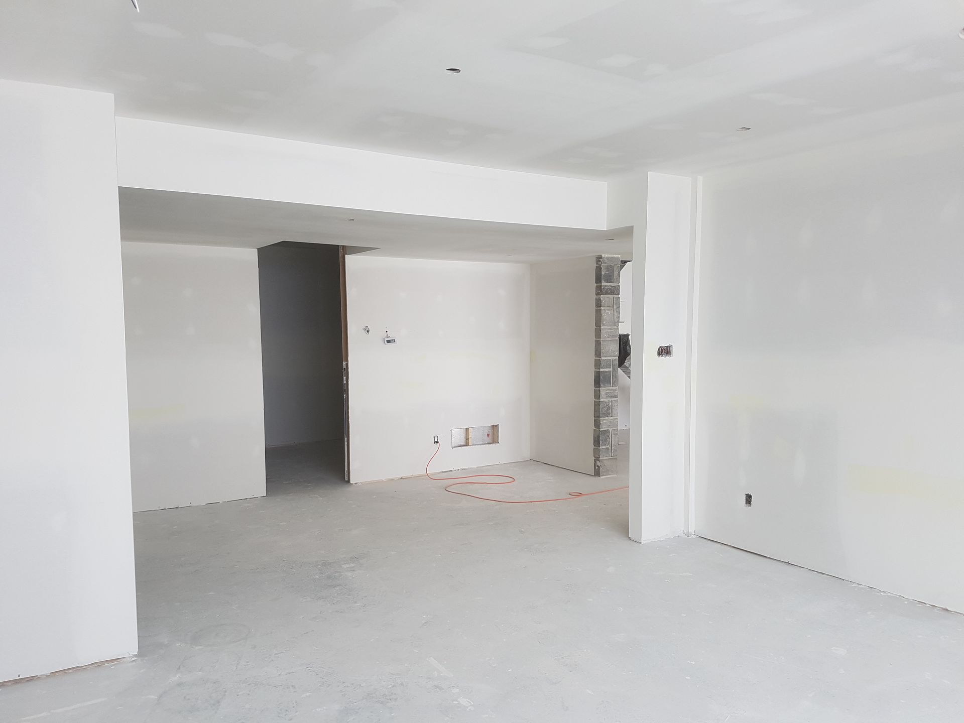 Une grande pièce vide avec des murs blancs et une porte.