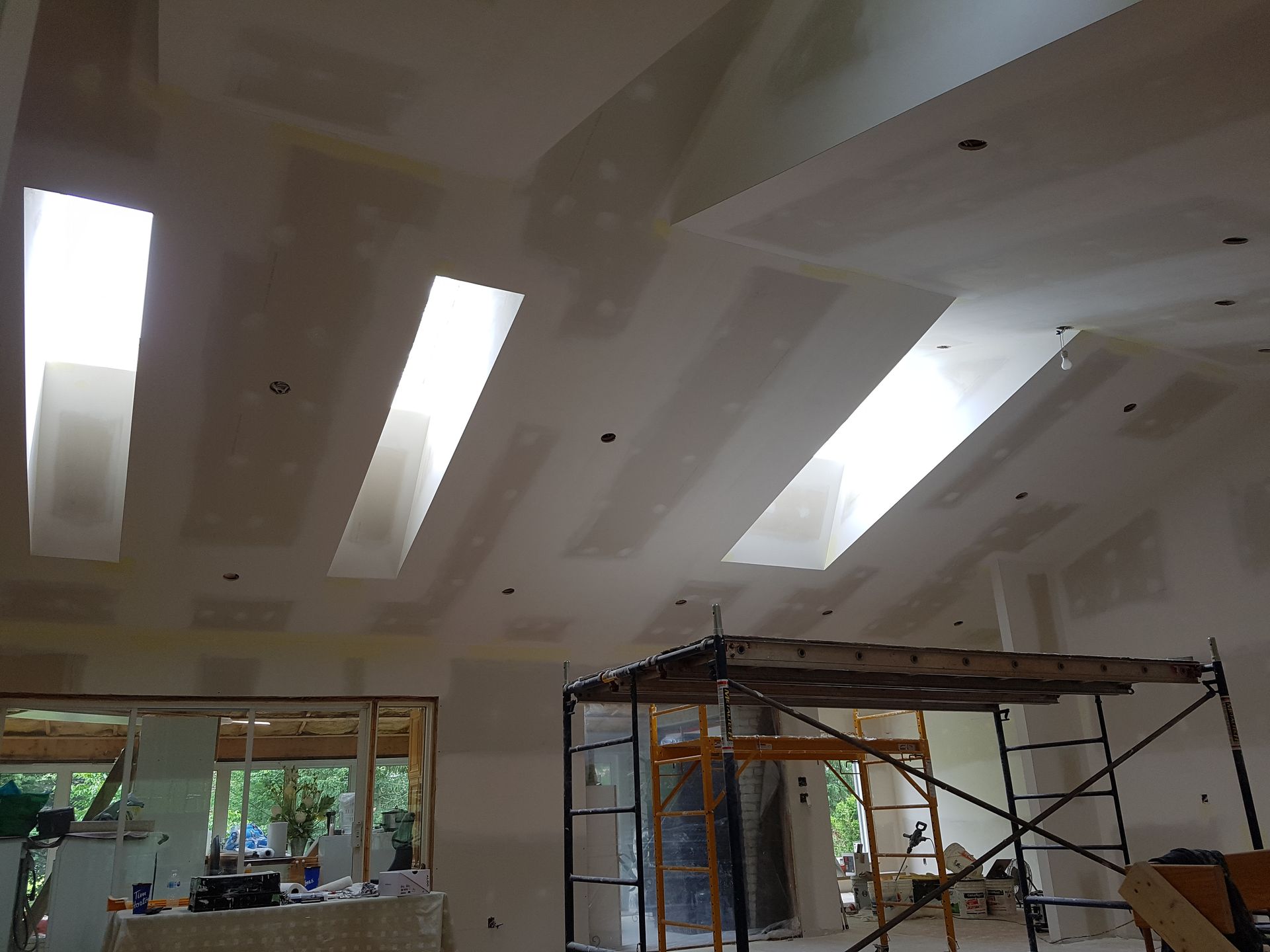 Une pièce en cours de rénovation avec beaucoup de fenêtres et d'échafaudages.