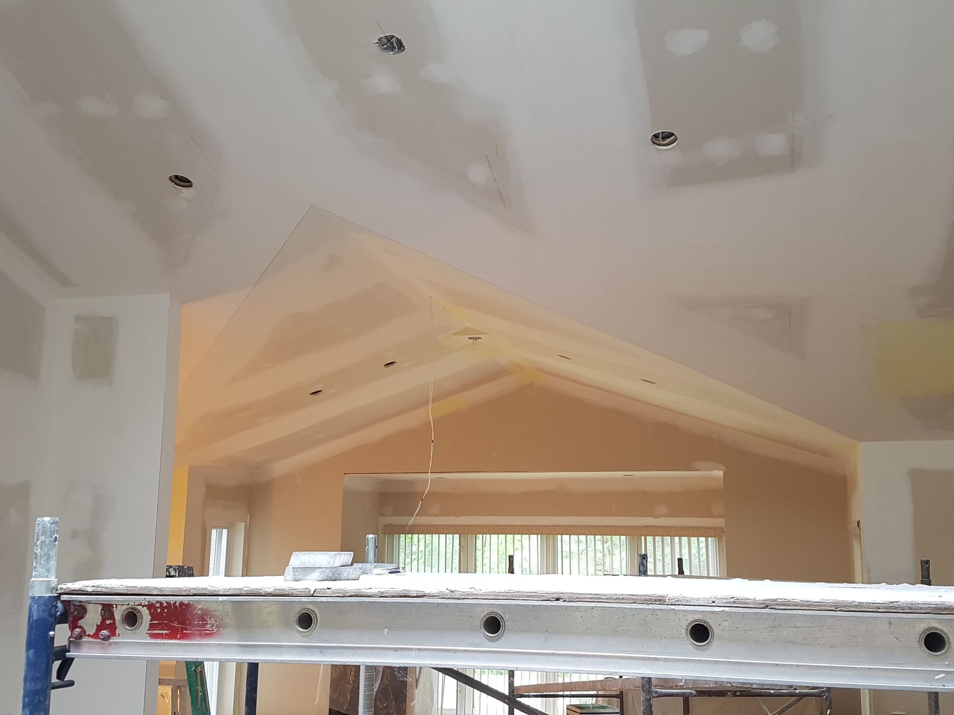 Une échelle est posée sur un échafaudage dans une pièce en construction.