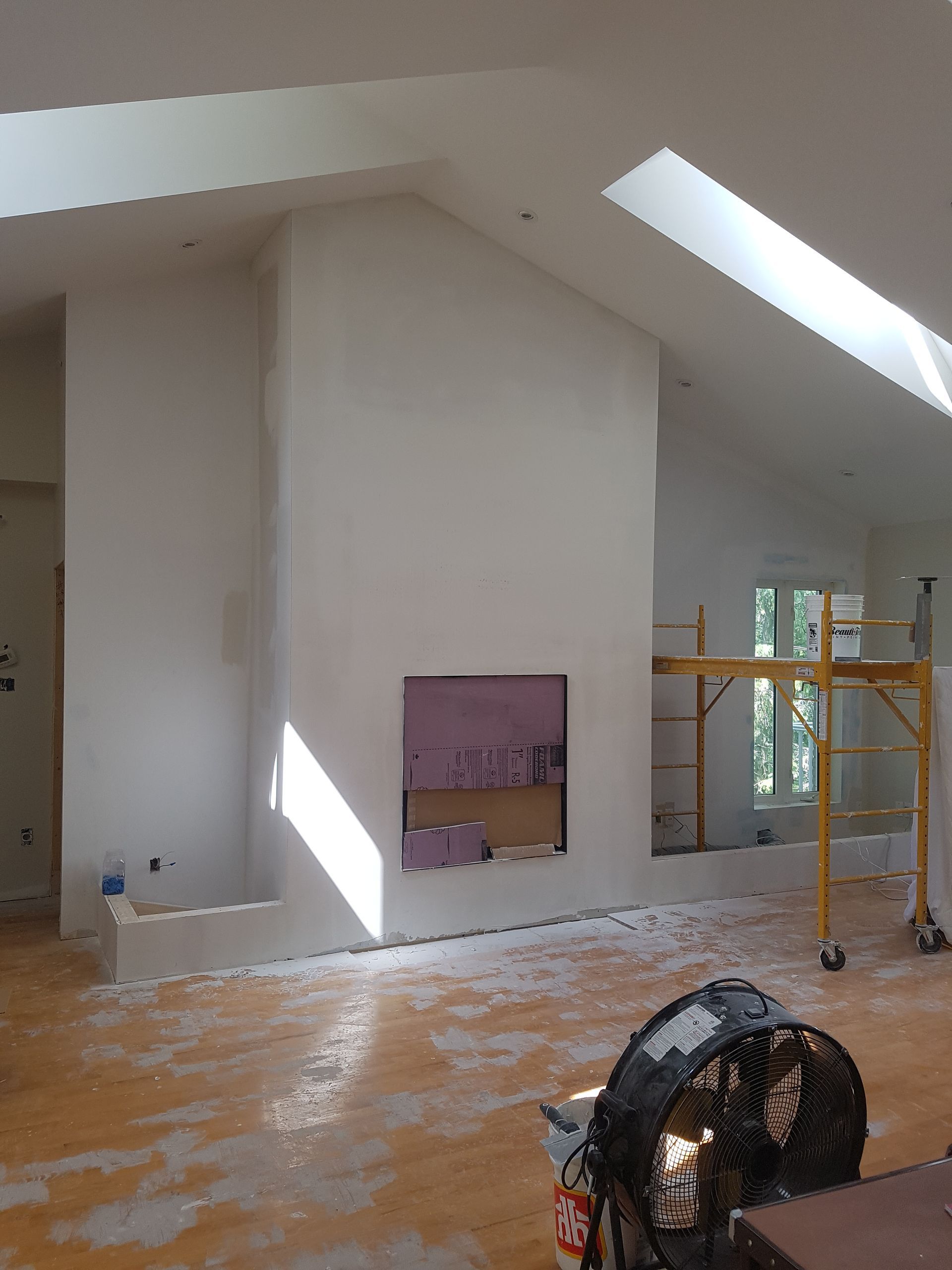 Une pièce en cours de rénovation avec un ventilateur au sol