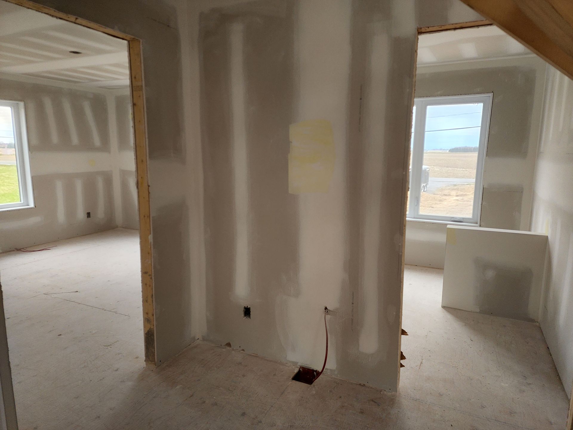 Une pièce vide avec des cloisons sèches sur les murs et une fenêtre.