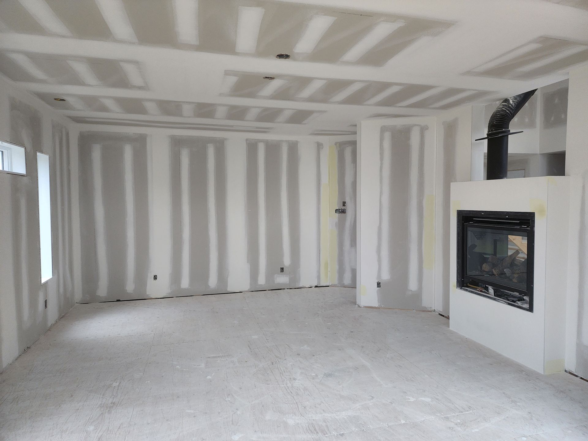 Une pièce vide avec des murs en plaques de plâtre et une cheminée