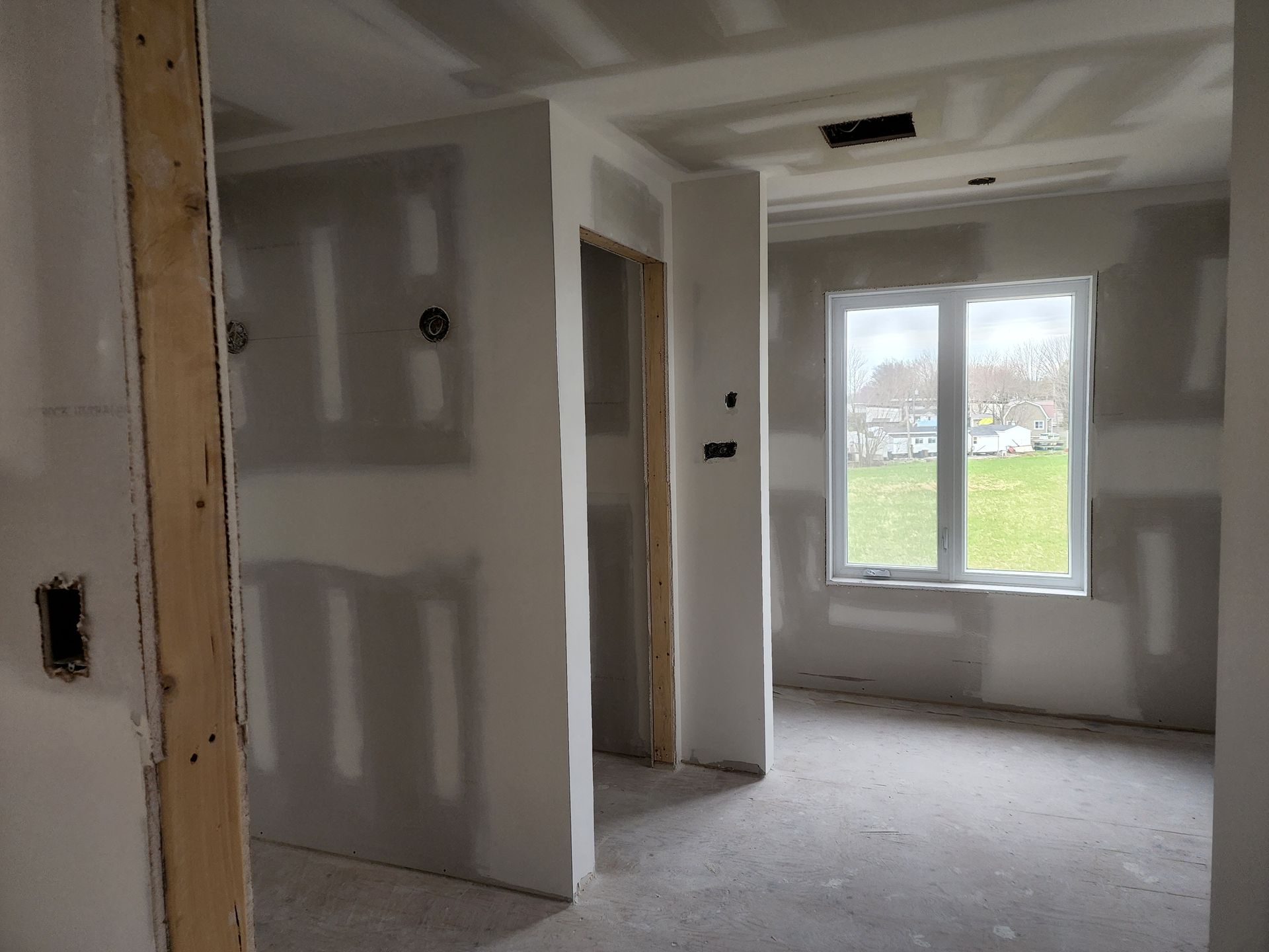 Une pièce vide avec des murs en plaques de plâtre et une fenêtre