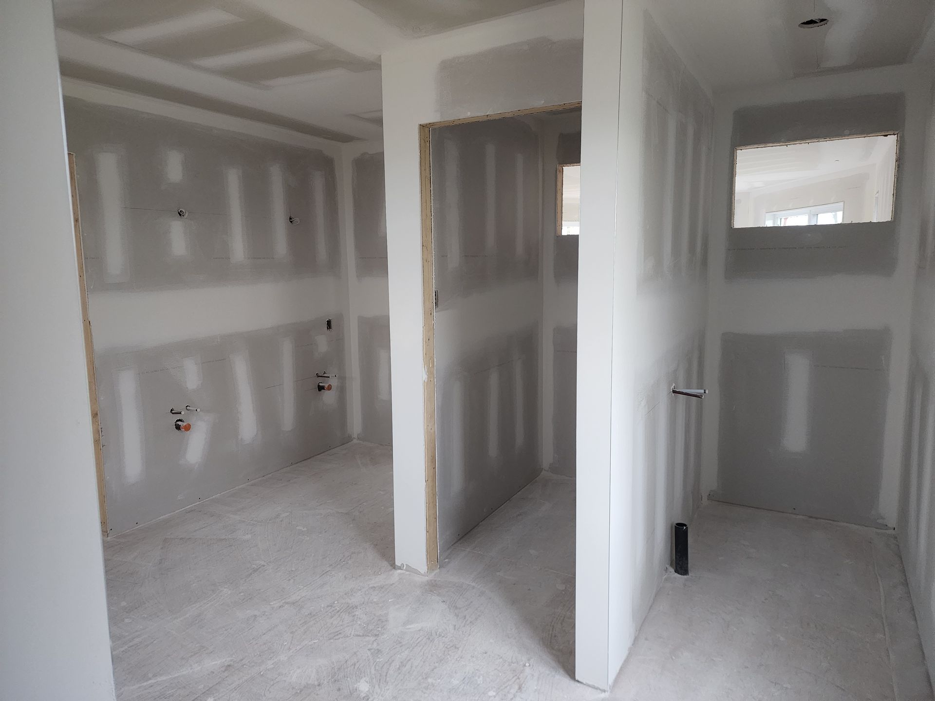 Une pièce vide avec des murs en plaques de plâtre et une fenêtre.