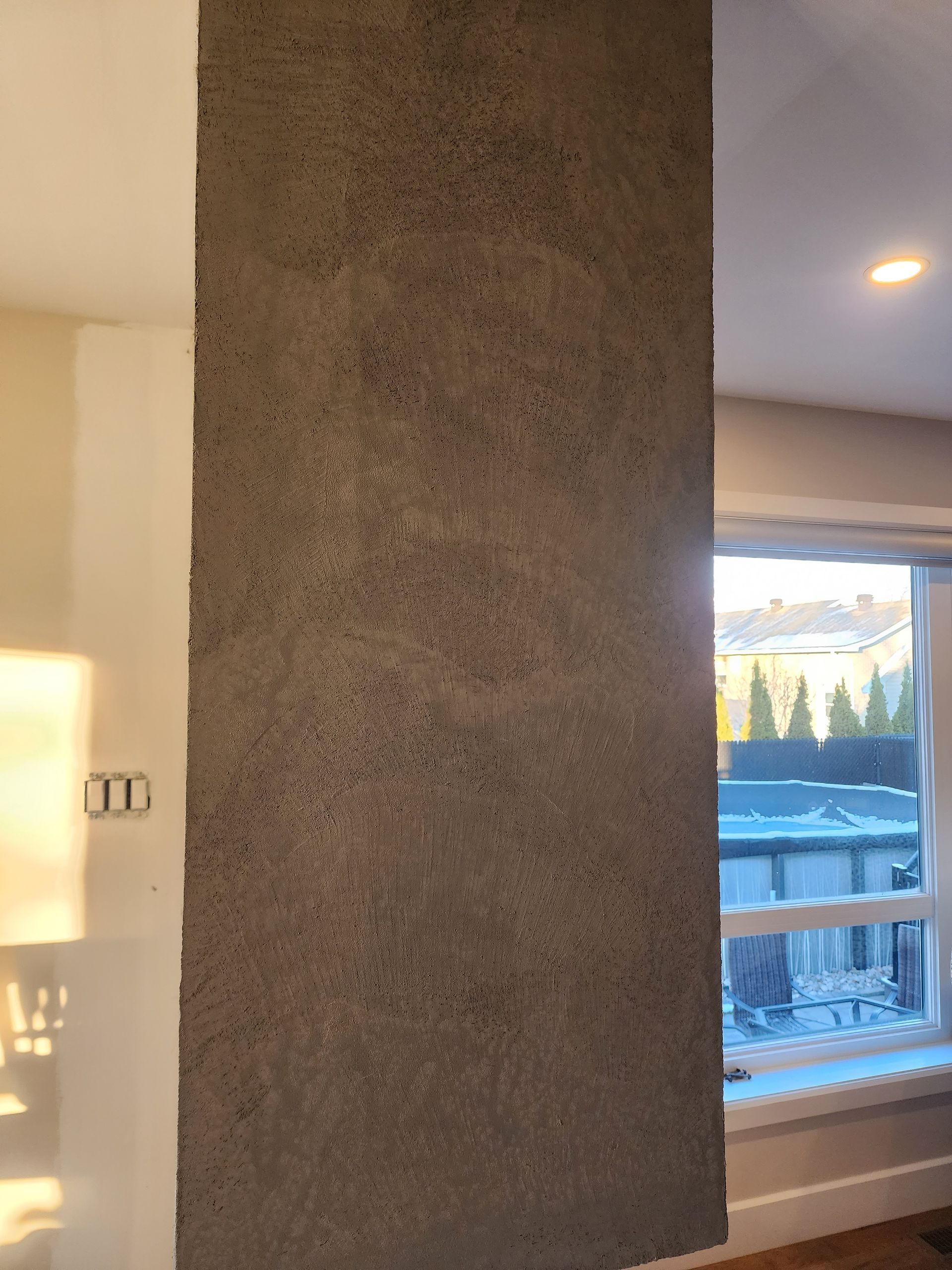 Une pièce avec un mur gris et une fenêtre.