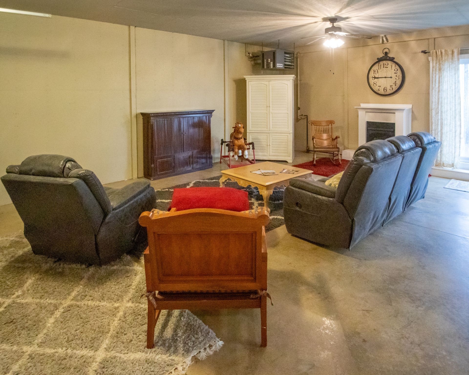 Living room with gray recliners, wooden furniture, fireplace, and large clock.