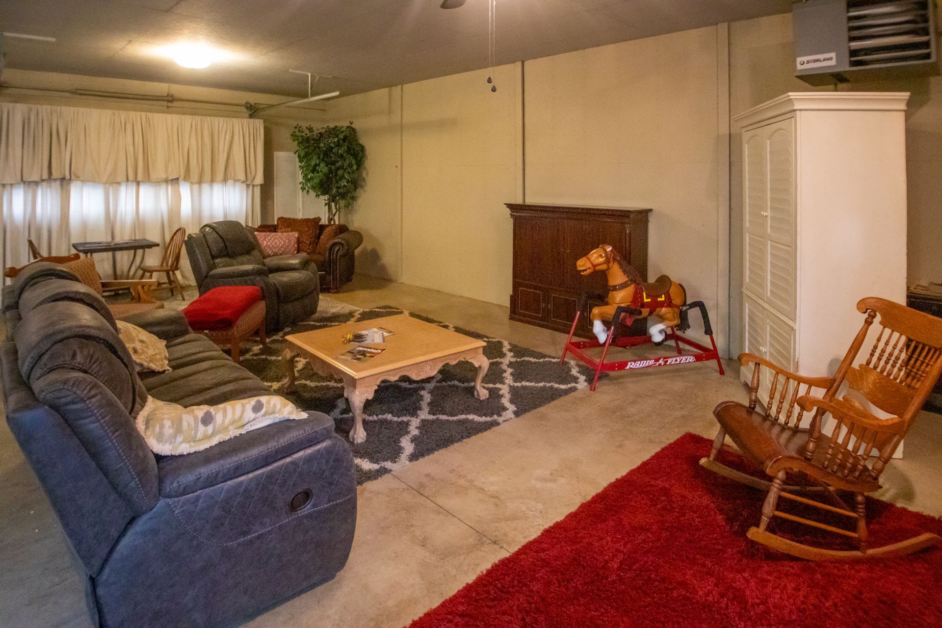Living room with couches, rug, rocking horse, and cabinet.