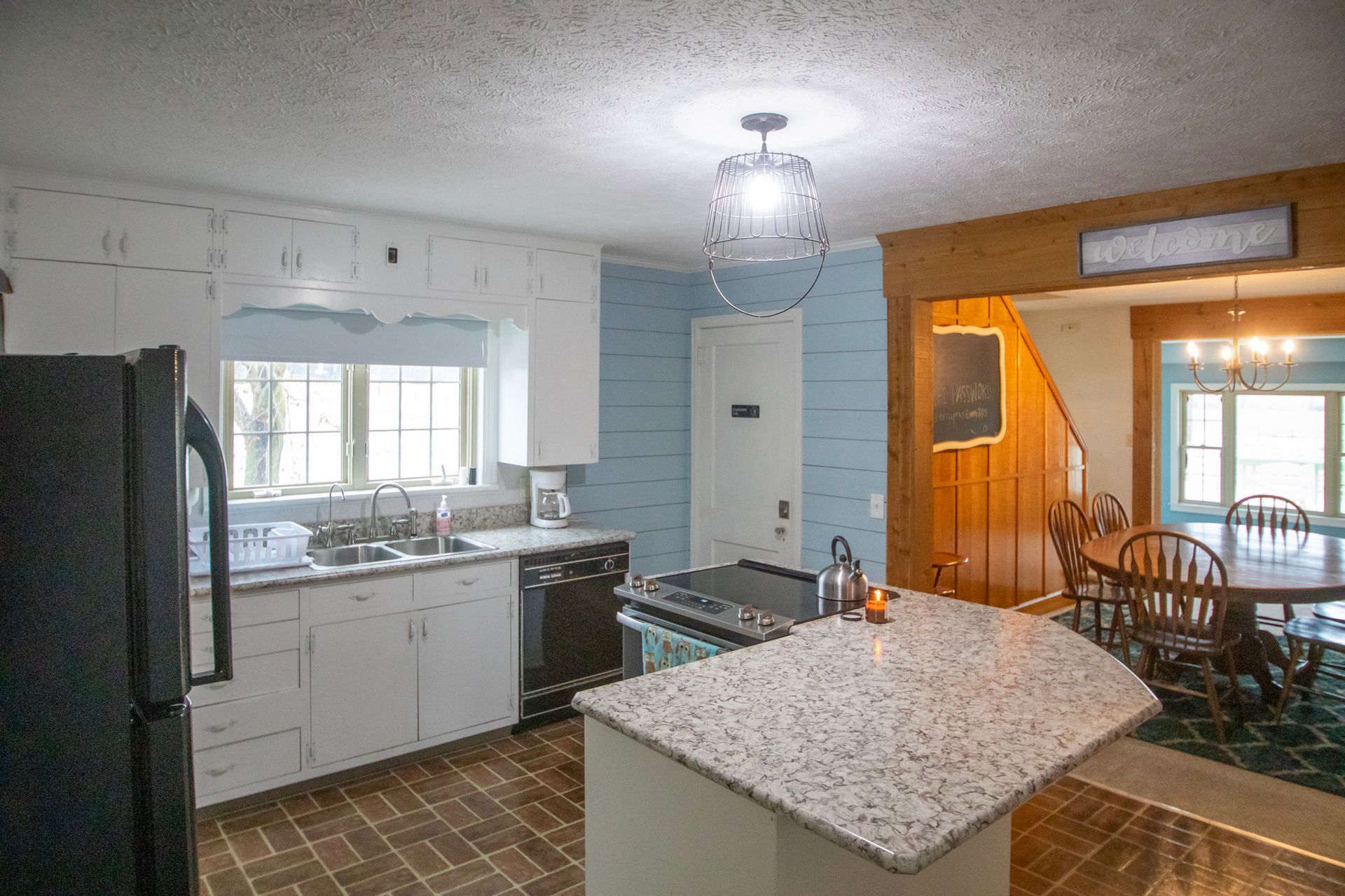 Kitchen with white cabinets, black appliances, granite island, and a dining area.