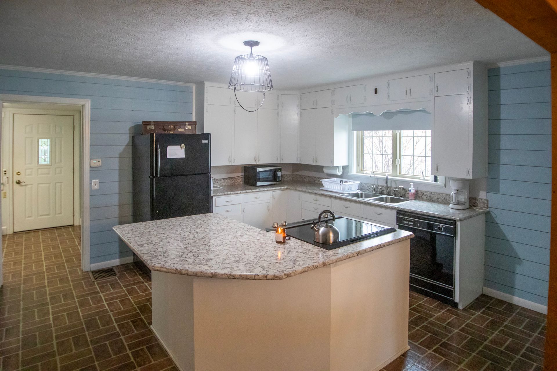 Kitchen with white cabinets, black appliances, granite countertops, and blue wall paneling.