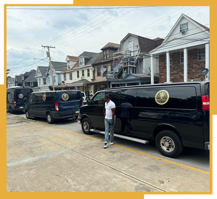 A man is standing in front of a row of vans parked on the side of the road.