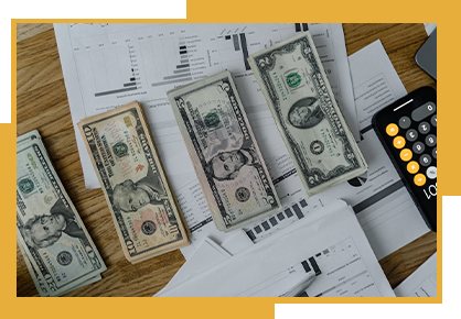 Three stacks of money are sitting on top of a wooden table.